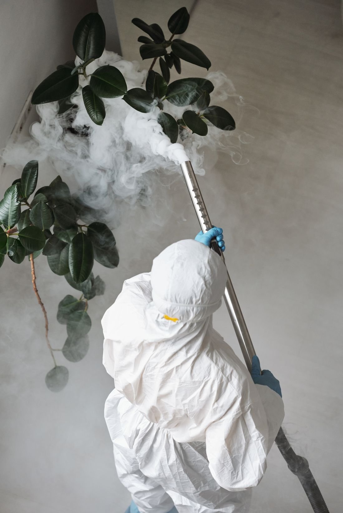Pest control technician spraying treatment around a home